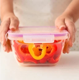 person closing a plastic container of sliced peppers